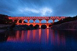 Acueducto romano iluminado sobre aguas tranquilas